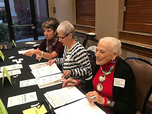 Osher volunteers work a registration table at an event. Osher volunteers work a registration table at an event.