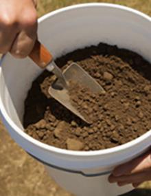 A man stirring soil in a bucket.