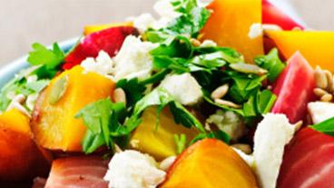 Close up view of a salad made from greens, fruit and cheese.